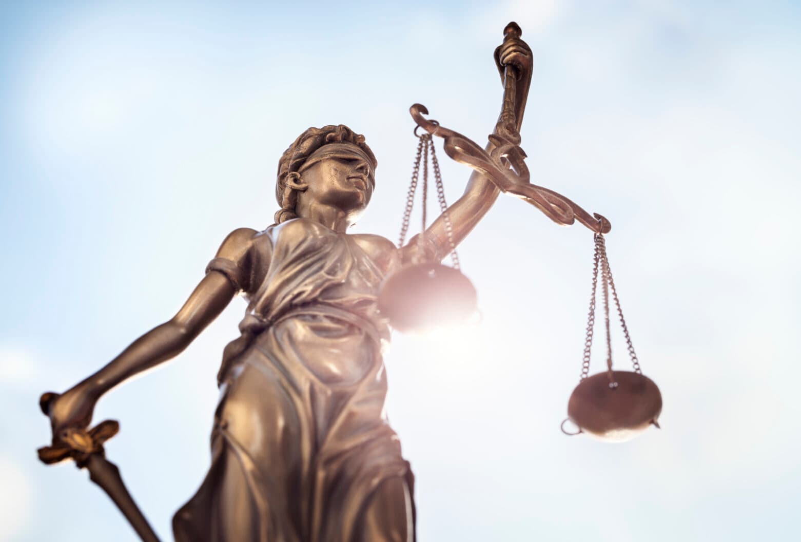 Scales of Justice statue against sky — representing EJC's 23-year pursuit of federal elder justice